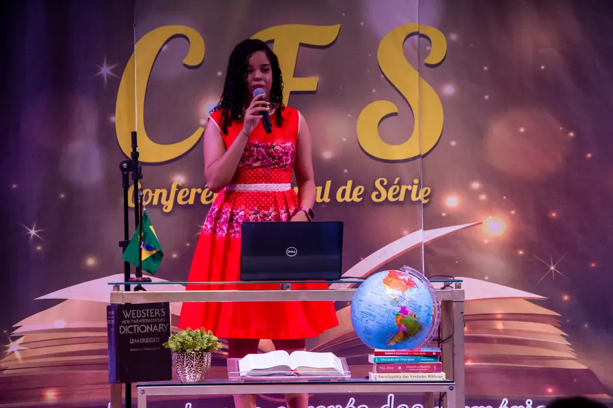Aluna apresenta sua pesquisa no púlpito, diante do painel da Conferência Final de Série